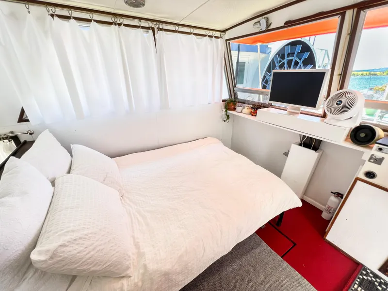 Slide: The Image of 1970 Tollycraft Tollyhome 36 interior with cozy bed, white curtains, and small desk area. - 3