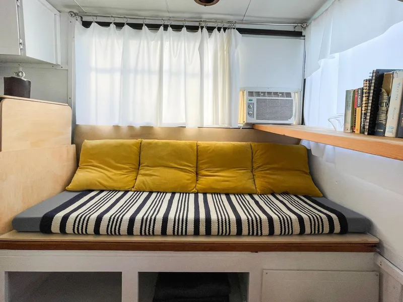 Slide: The Image of 1970 Tollycraft Tollyhome 36 interior with cozy seating, striped cushion, yellow pillows, and bookshelf. - 42