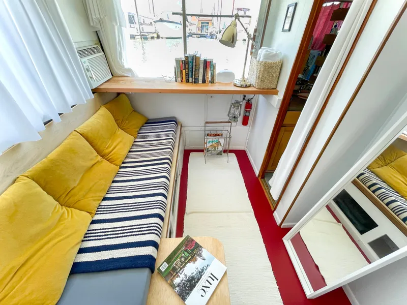 Slide: The Image of 1970 Tollycraft Tollyhome 36 interior with cozy seating, striped blanket, and books by the window. - 45