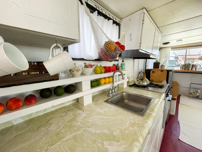 Slide: The Image of 1970 Tollycraft Tollyhome 36 kitchen with fruit, sink, and stove in a cozy setting. - 7