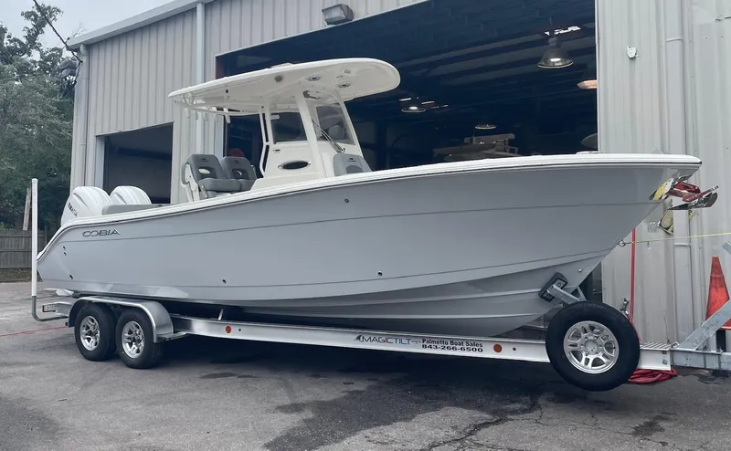 The Image of 2024 Cobia 262 Center Console boat on trailer outside a warehouse. - 0