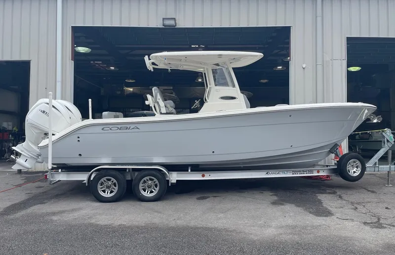 Slide: The Image of 2024 Cobia 262 Center Console boat on a trailer outside a warehouse. - 1