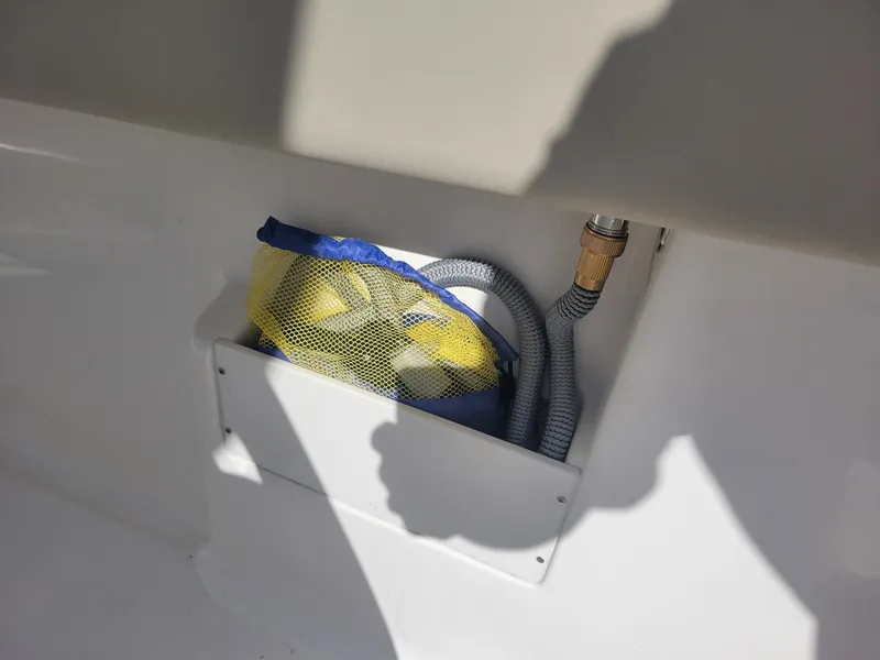 Slide: The Image of Storage compartment on a 2024 Key West 239 FS boat with hose and mesh bag. - 12