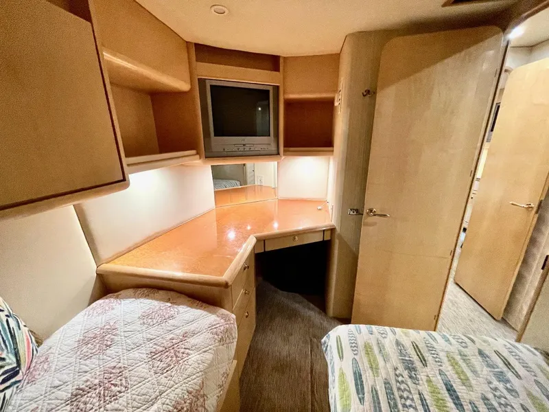 Slide: The Image of 2003 Ocean Yachts 62 Convertible bedroom with built-in desk, TV, and storage shelves. - 24