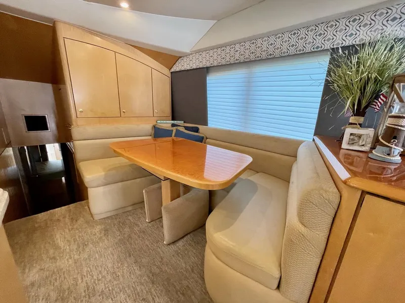Slide: The Image of 2003 Ocean Yachts 62 Convertible interior dining area with wooden table and cushioned seating. - 8
