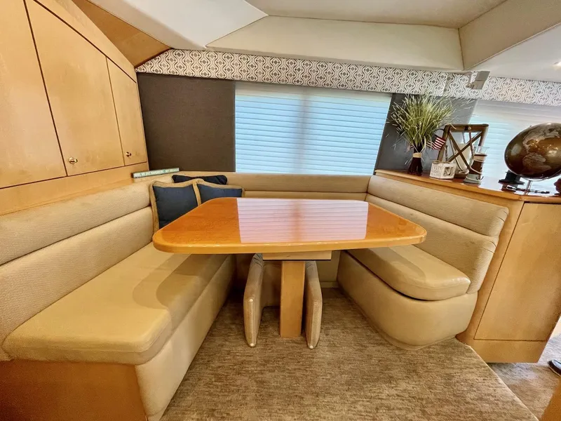 Slide: The Image of Dining area in 2003 Ocean Yachts 62 Convertible with beige seating and wooden table. - 9