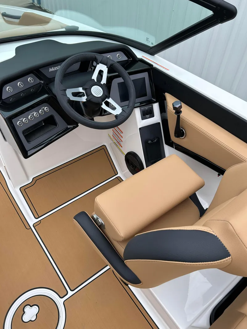 Slide: The Image of 2024 MasterCraft NXT 24 boat interior with tan and black seating, modern dashboard, and steering wheel. - 8