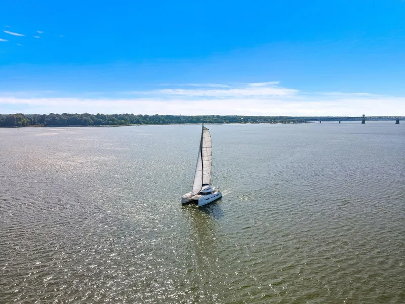 Slide: The Image of Sailing catamaran Nautitech 46 Open, 2017 model, gliding on a serene waterway under a clear blue sky. - 12