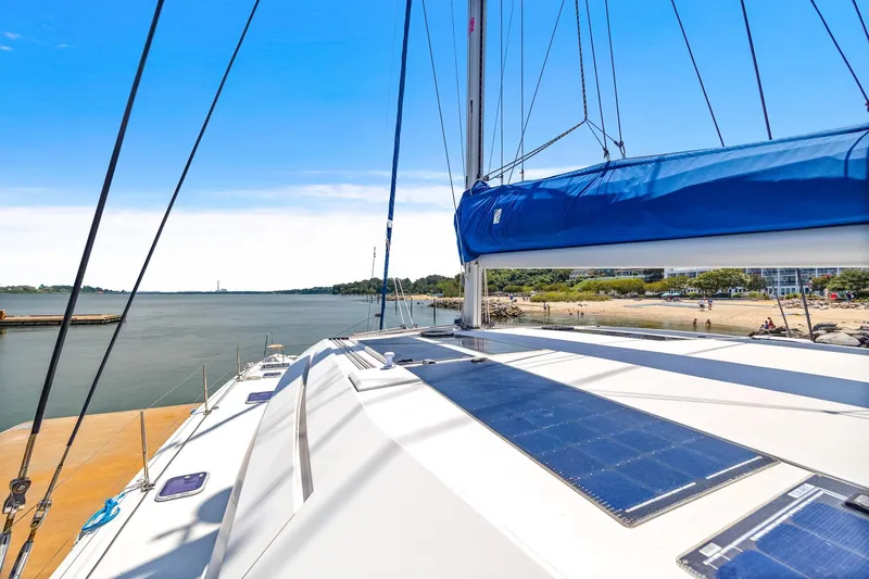 Slide: The Image of 2017 Nautitech 46 Open catamaran with solar panels, docked by a scenic shoreline. - 33