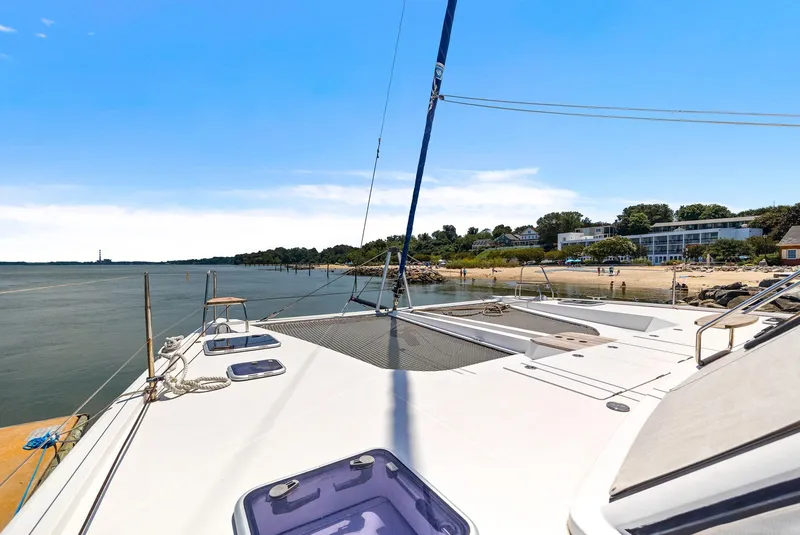 Slide: The Image of 2017 Nautitech 46 Open catamaran docked by a scenic shoreline under a clear blue sky. - 40