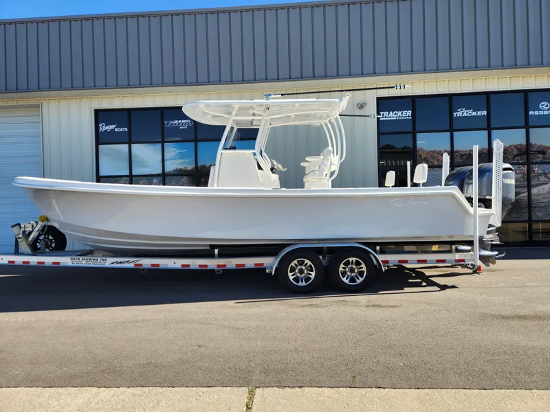 The Image of 2024 Pair Customs 27 CC boat on trailer, parked outdoors with trees in background. - 0