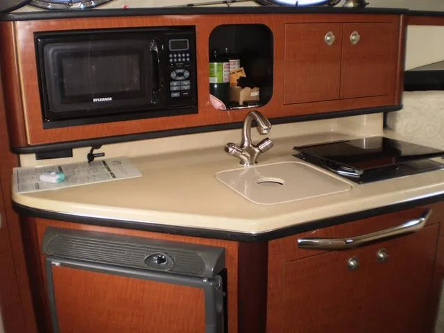 Slide: The Image of 2005 Sea Ray 260 Sundancer galley with microwave, sink, and storage cabinets. - 12