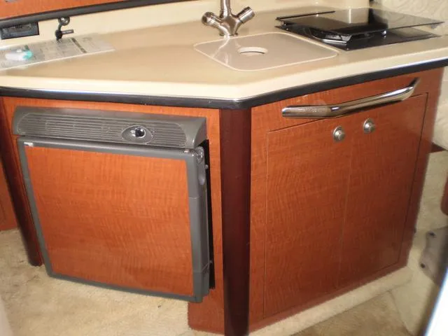 Slide: The Image of Compact kitchen area in a 2005 Sea Ray 260 Sundancer boat with sink and mini-fridge. - 13