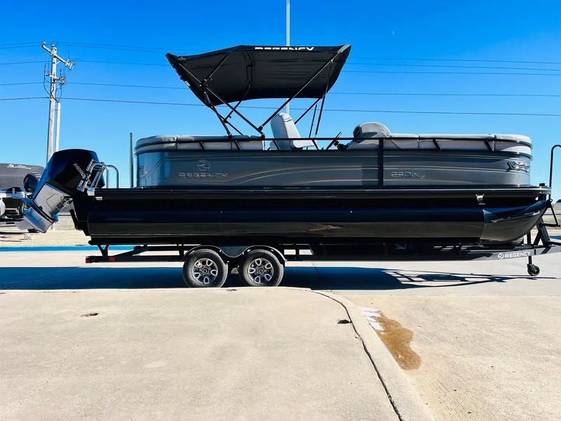 Slide: The Image of 2024 Regency 230 DL3 pontoon boat on a trailer, black and gray exterior. - 5