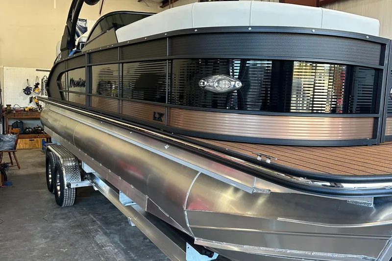 The Image of 2024 Manitou 25LX SRW pontoon boat in a garage. - 0
