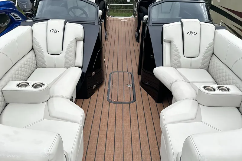 Slide: The Image of 2024 Manitou 25LX SRW boat interior with luxurious white seating and wood-like flooring. - 10
