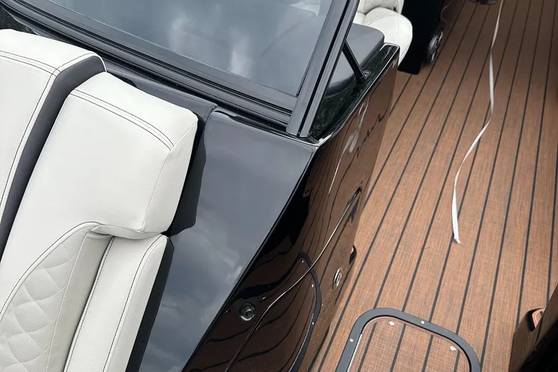 Slide: The Image of 2024 Manitou 25LX SRW boat interior with beige seats and wooden deck. - 11