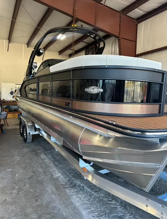Slide: The Image of 2024 Manitou 25LX SRW pontoon boat in a storage facility. - 9