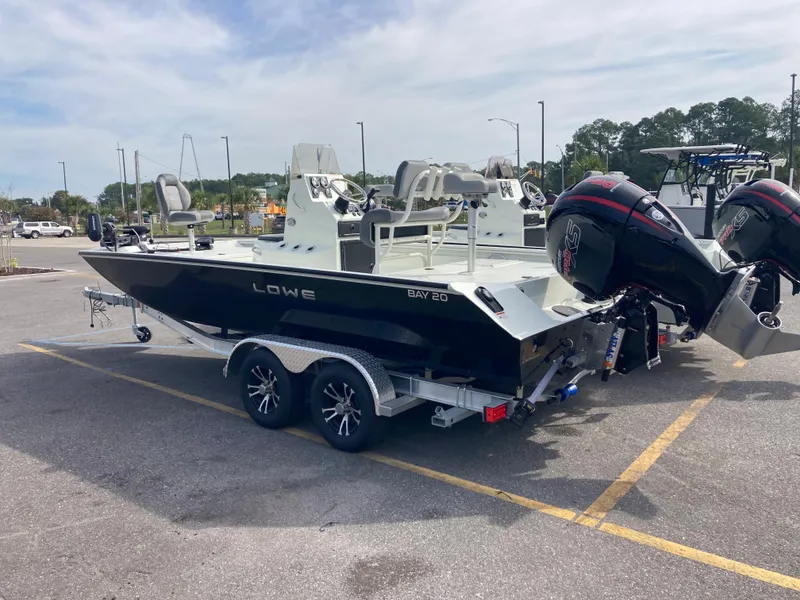 Slide: The Image of 2023 Lowe BAY 20 boat on a trailer in a parking lot. - 1