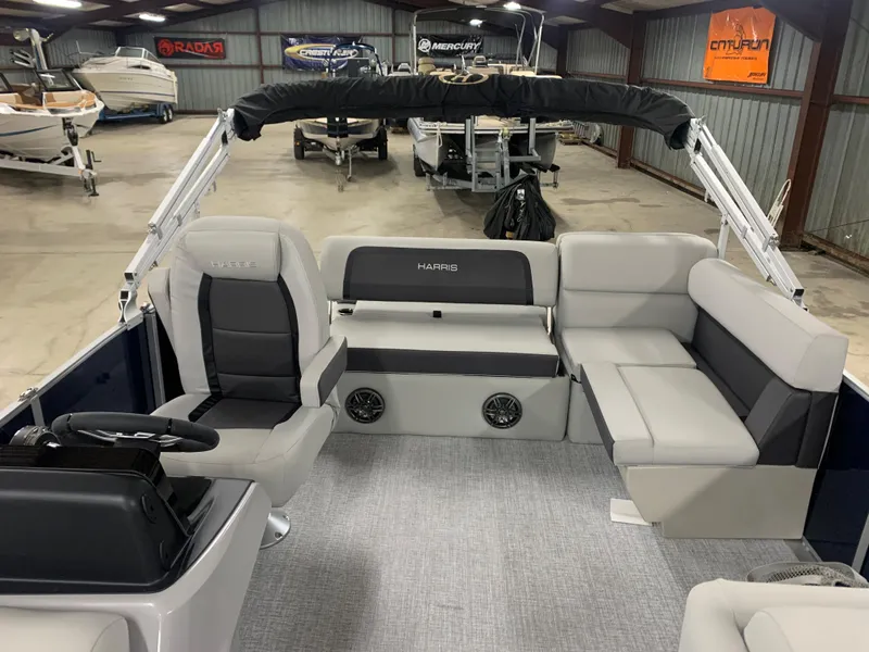 Slide: The Image of 2024 Harris Cruiser 190 pontoon boat interior with gray seating in a showroom. - 2