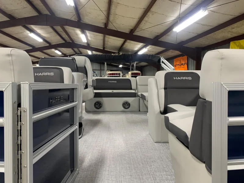 Slide: The Image of 2024 Harris Cruiser 190 pontoon boat interior with spacious seating in a well-lit warehouse. - 8