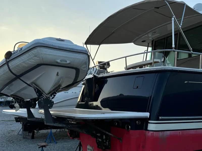 Slide: The Image of 2012 Sabre 48 Salon Express yacht with dinghy on lift, docked outdoors. - 1