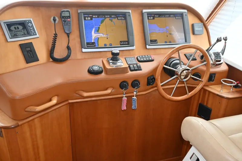 Slide: The Image of 2012 Sabre 48 Salon Express helm with dual navigation screens and wooden steering wheel. - 2