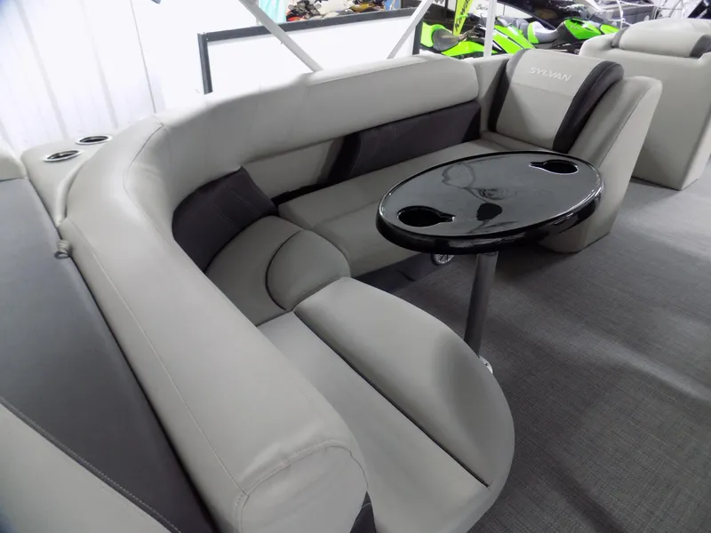 Slide: The Image of 2024 Sylvan 8522 Mirage Cruise boat interior with plush seating and a sleek black table. - 5