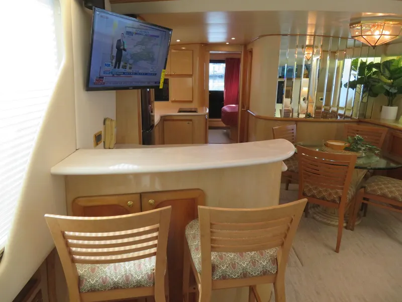 Slide: The Image of Interior of 2000 Bluewater Yachts 5800 Motor Yacht with bar, dining area, and mounted TV. - 21