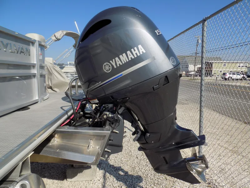 Slide: The Image of 2024 Sylvan Mirage 8522 LZ with Yamaha outboard motor, parked near a chain-link fence. - 4