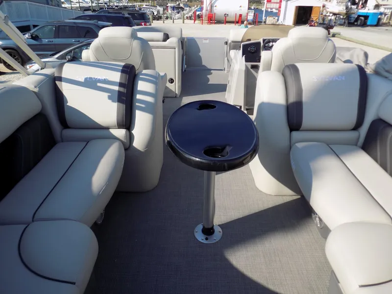 Slide: The Image of 2024 Sylvan Mirage 8522 LZ pontoon boat interior with plush seating and central table. - 5