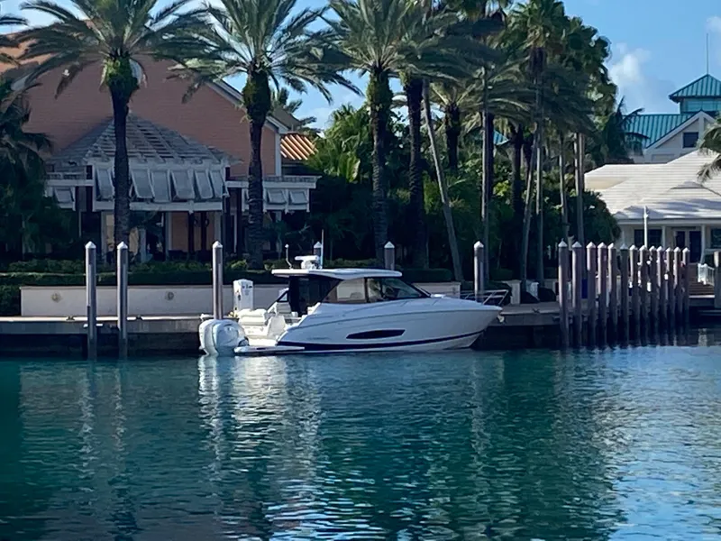 Slide: The Image of 2023 Regal 36 XO yacht docked by palm trees and waterfront buildings. - 10