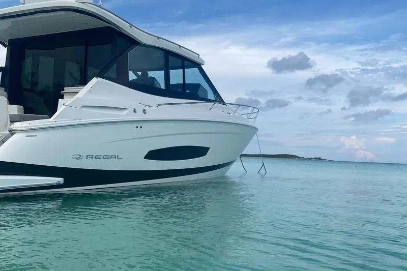 Slide: The Image of 2023 Regal 36 XO boat anchored in clear turquoise water. - 21