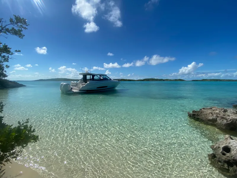 Slide: The Image of 2023 Regal 36 XO boat anchored in clear turquoise waters under a bright blue sky. - 5