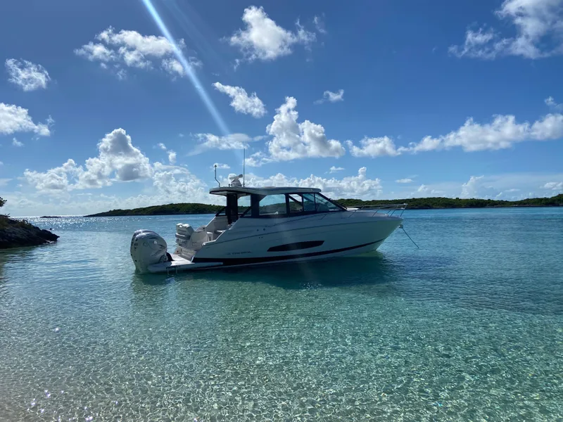 Slide: The Image of 2023 Regal 36 XO boat anchored in clear turquoise water under a sunny sky. - 6