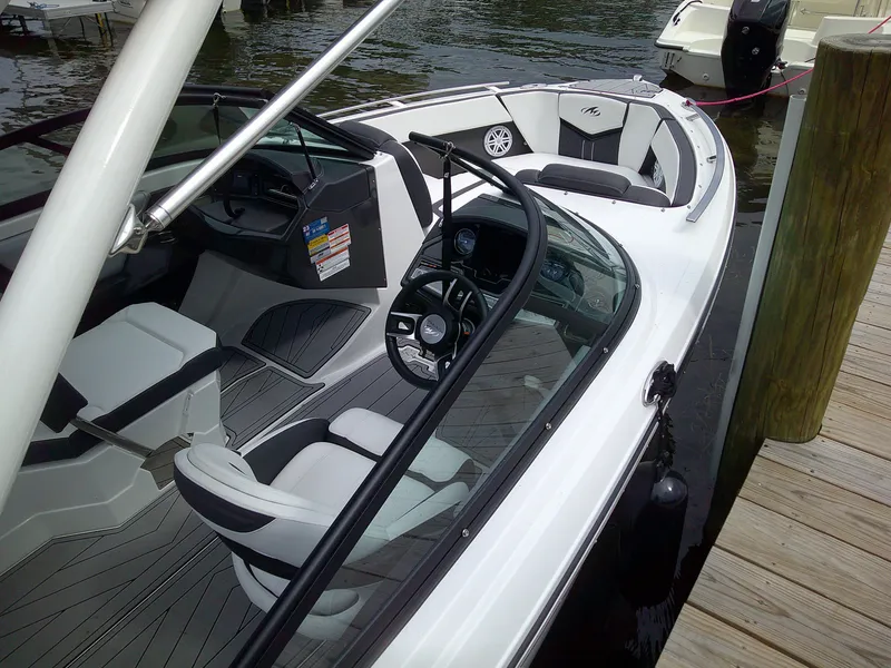Slide: The Image of 2023 Monterey 218 SS Bowrider boat docked, showcasing interior seating and steering wheel. - 6