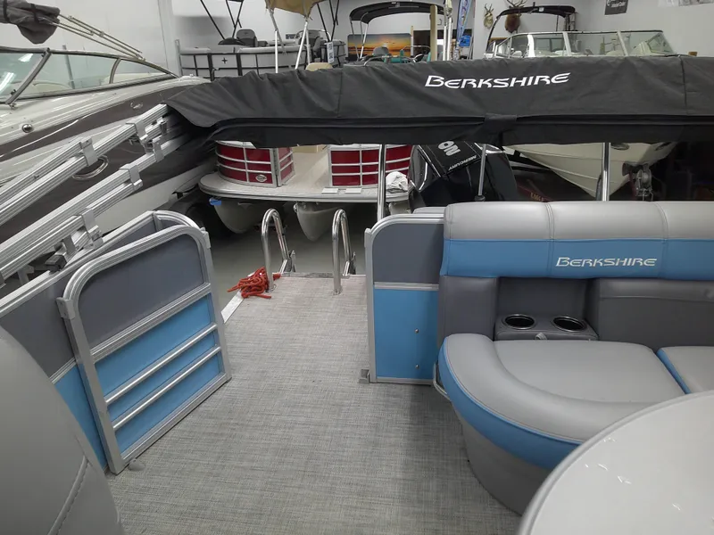Slide: The Image of 2022 Berkshire 22CL2 CTS pontoon boat interior with blue and gray seating, docked in a showroom. - 7