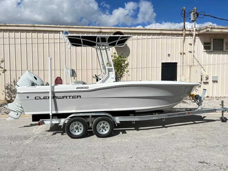 Slide: The Image of 2024 Clearwater 2000 boat on a trailer, parked outdoors under a blue sky. - 6