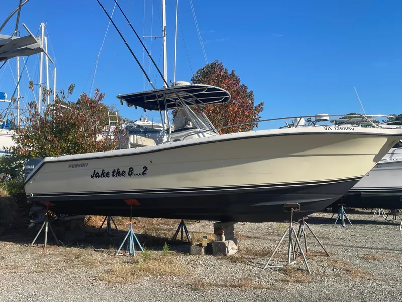 Slide: The Image of 2004 Pursuit 2670 Cuddy Console boat on stands in a marina. - 2