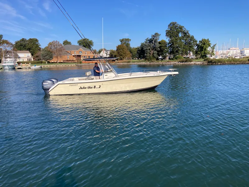 Slide: The Image of 2004 Pursuit 2670 Cuddy Console boat cruising on a calm lake with scenic background. - 29
