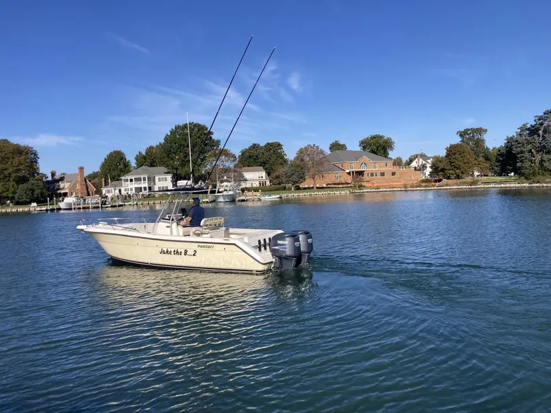 Slide: The Image of 2004 Pursuit 2670 Cuddy Console boat cruising on a calm lake near waterfront homes. - 30