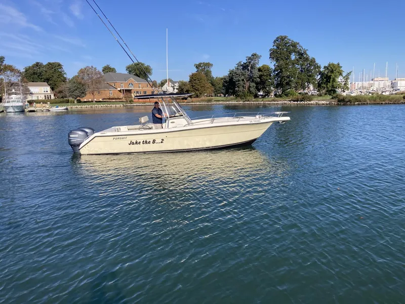 Slide: The Image of 2004 Pursuit 2670 Cuddy Console boat cruising on a calm lake near a residential area. - 4