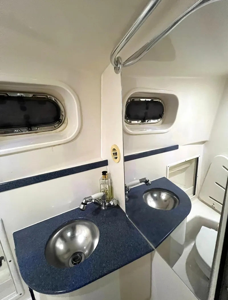 Slide: The Image of 2005 Pursuit 3070 Offshore bathroom with dual sinks and porthole windows. - 13