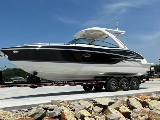 Slide: The Image of 2024 Formula 310 CBR boat on a trailer, parked on a rocky shore. - 0