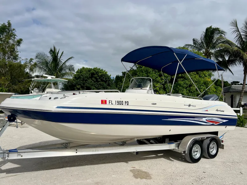 Slide: The Image of 2011 Hurricane 231 boat on trailer with blue canopy, parked outdoors. - 2
