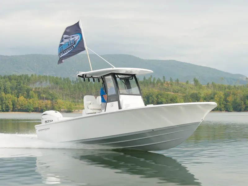 Slide: The Image of 2024 Sportsman Masters 267OE Bay boat cruising on a serene lake with scenic mountain backdrop. - 20