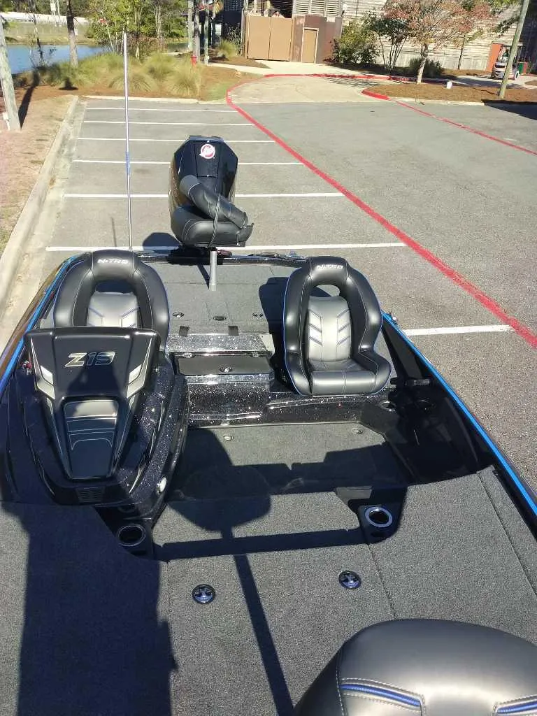 Slide: The Image of 2024 Nitro Z19 Pro bass boat with dual seats and outboard motor in parking lot. - 5