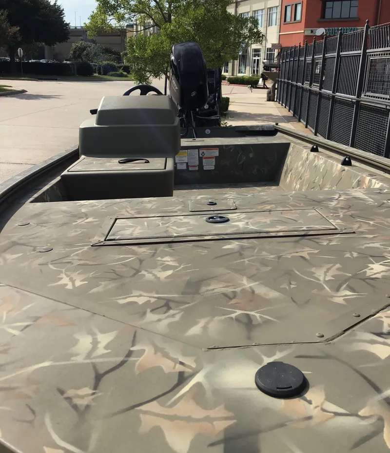 Slide: The Image of 2024 Tracker Grizzly 1648 SC boat with camouflage design, parked outdoors. - 2