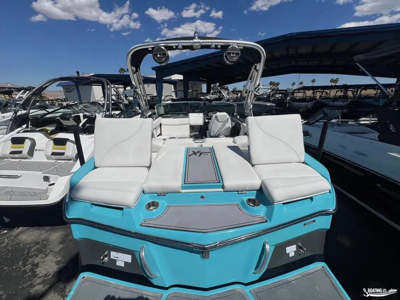 Slide: The Image of 2018 MasterCraft XT22 boat with white seating and turquoise exterior, docked among other boats. - 4