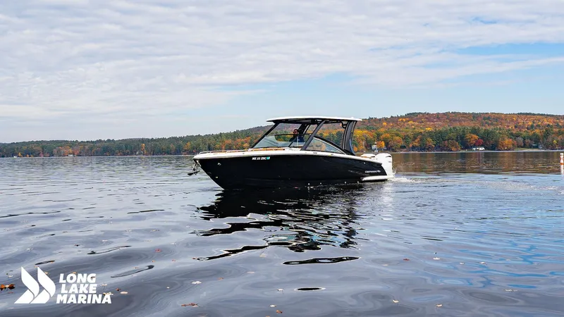 Slide: The Image of 2024 Chaparral 300 OSX boat cruising on a scenic lake with autumn foliage. - 1